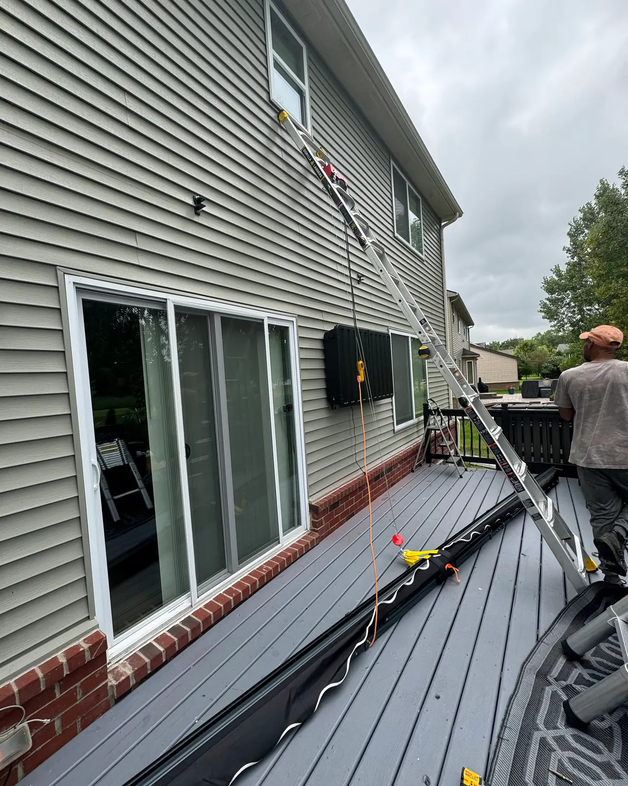 Awning frame being mounted above a sliding door on a gray deck