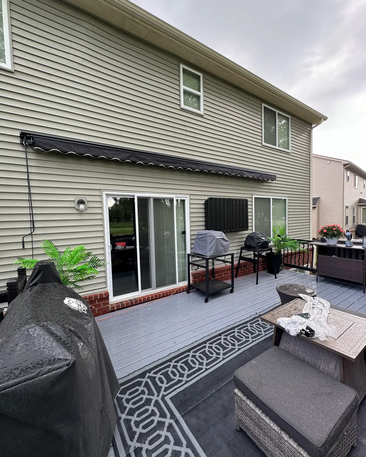 Awning over a sliding door and gray deck with patio furniture