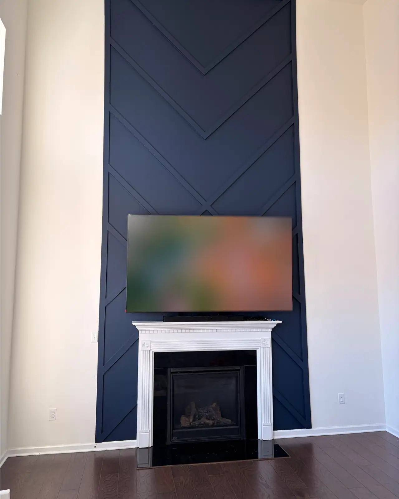 Floor-to-ceiling navy accent wall with chevron trim above a white fireplace mantel