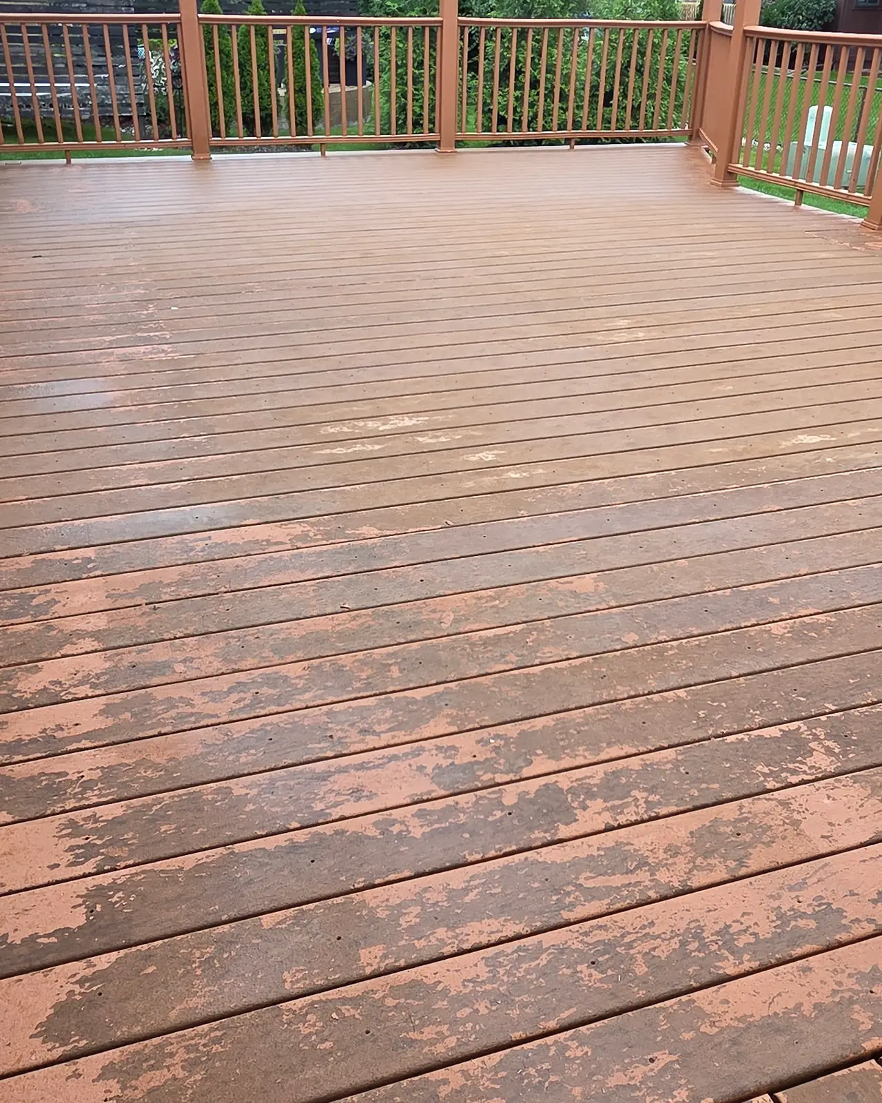Wood deck with worn, peeling stain on the boards and railings, before