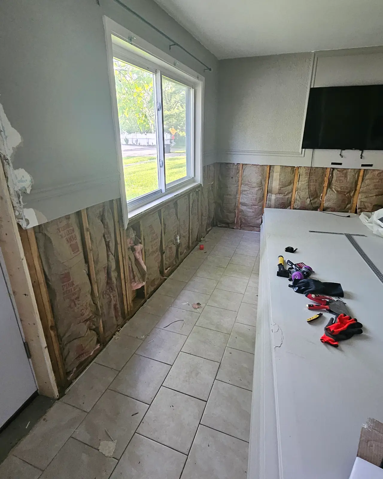 Room with lower walls opened to the studs and insulation, before