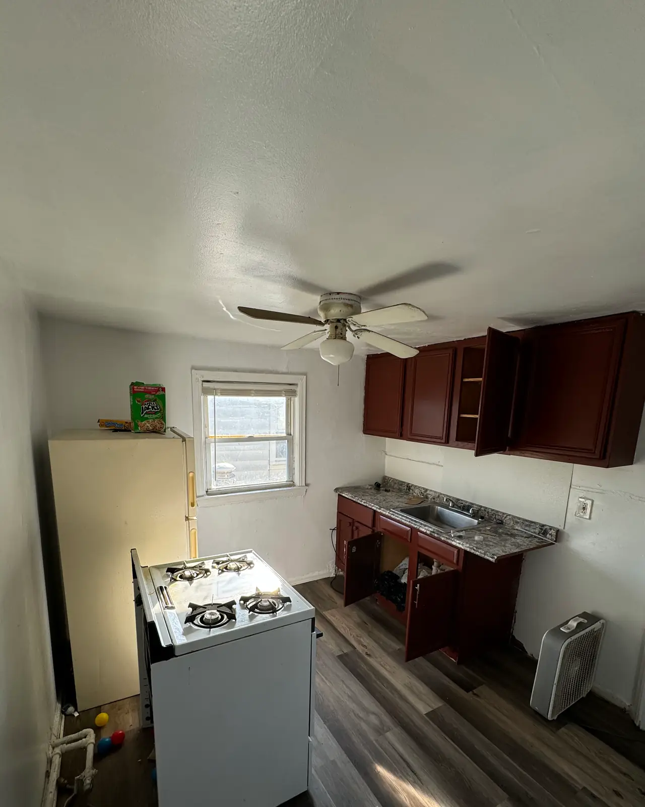 Narrow kitchen with dark wood cabinets and a white range, before