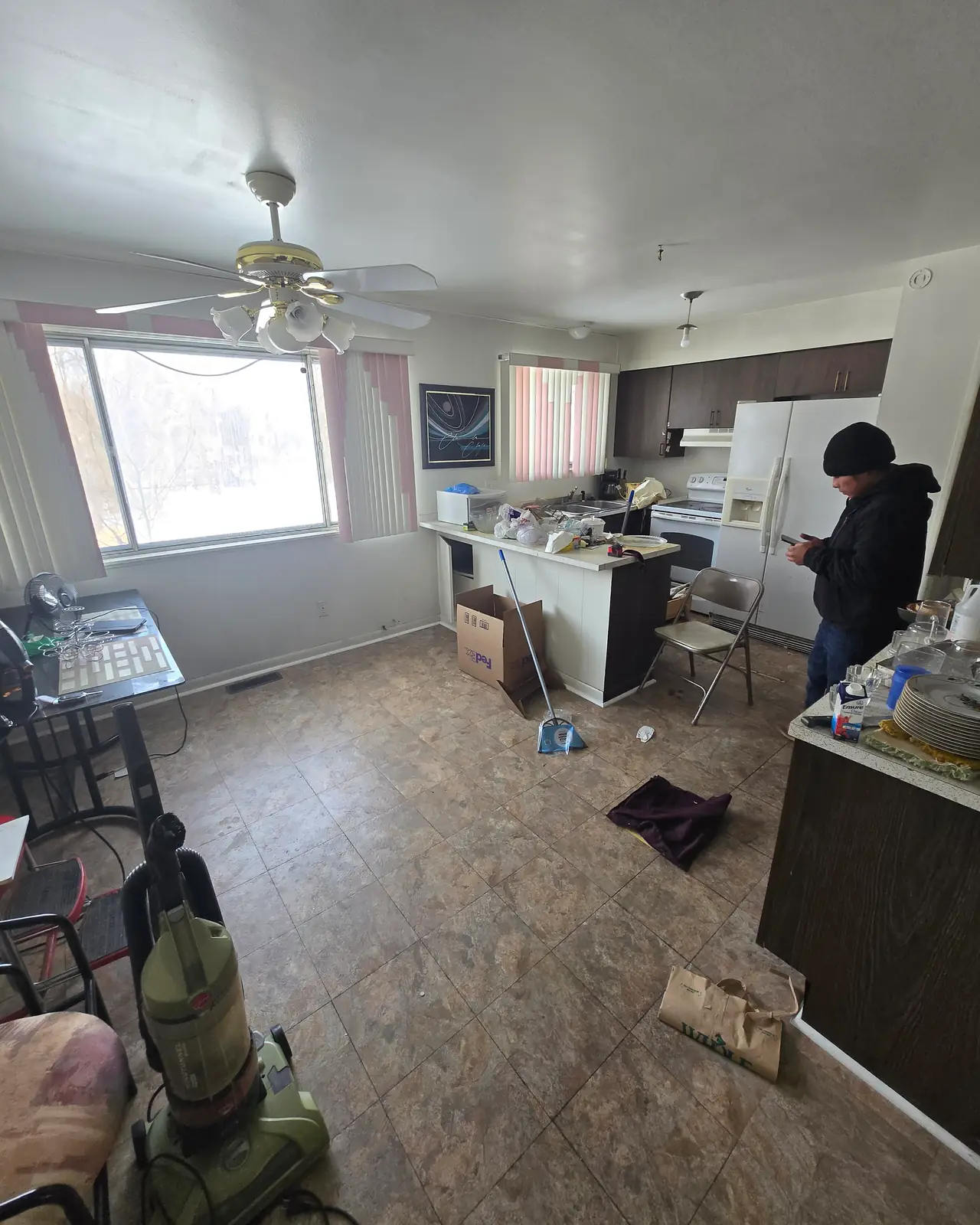 Kitchen and dining area with older cabinets and items on the floor, before