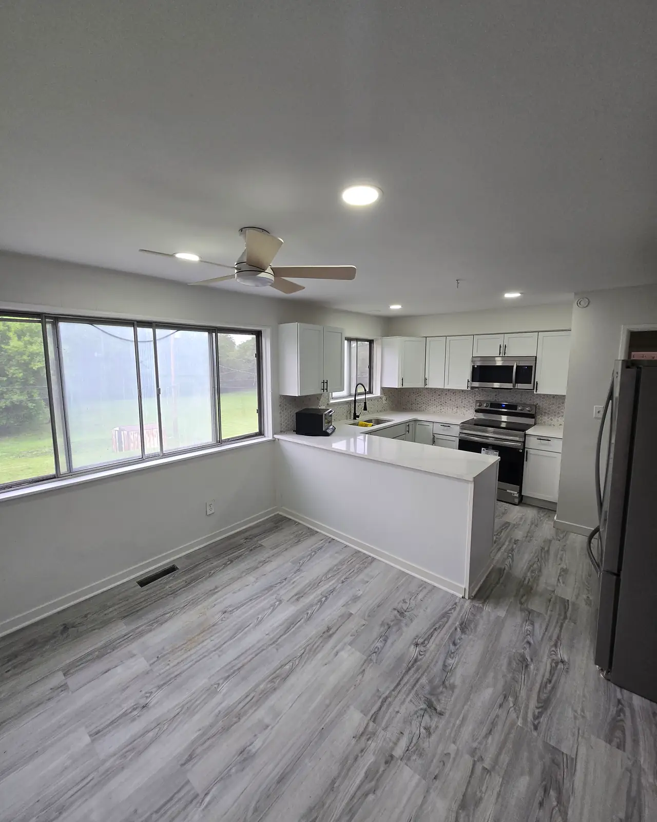Kitchen with white cabinets, a white peninsula and gray plank flooring