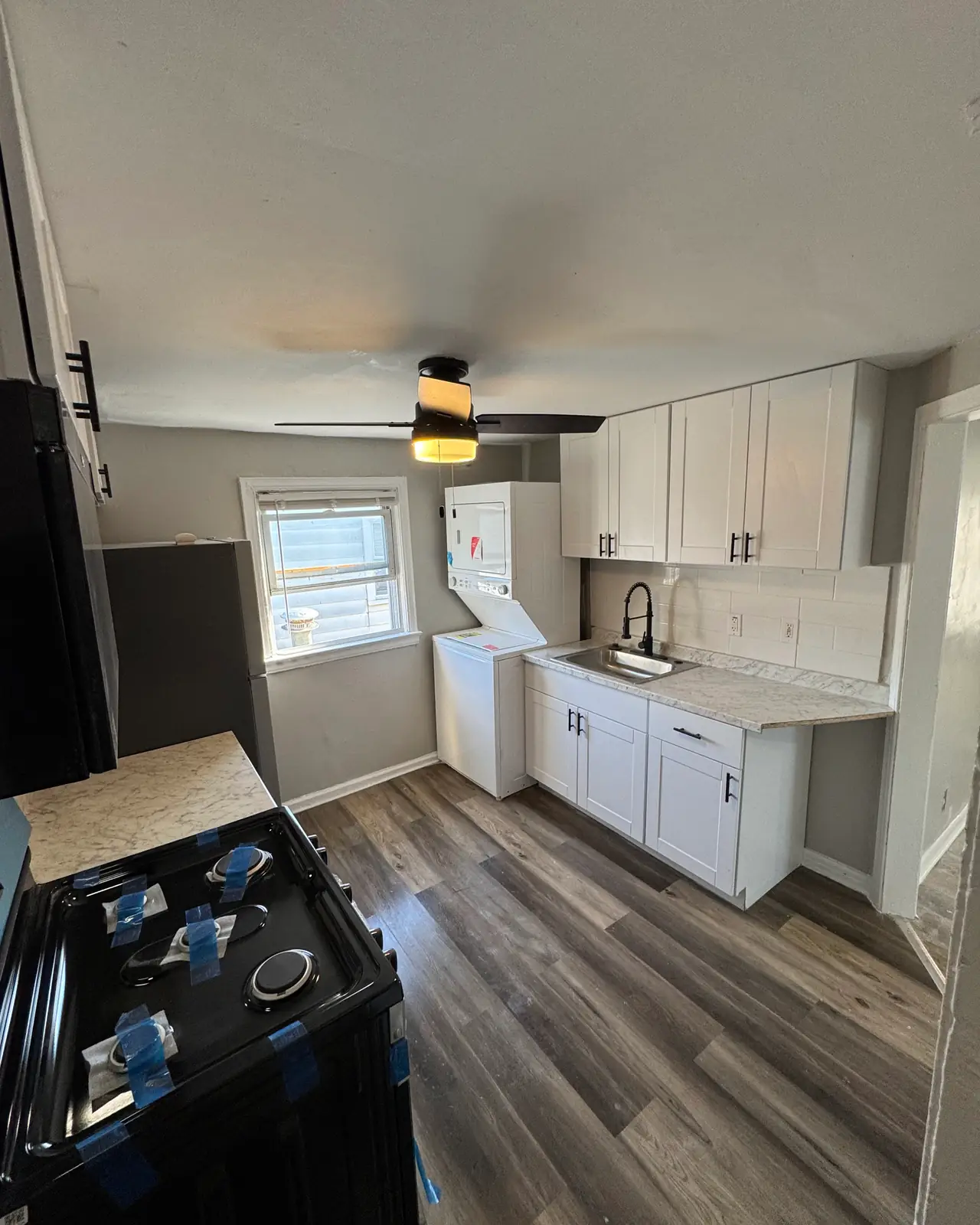 Narrow kitchen with white shaker cabinets, gray countertop and plank flooring, after