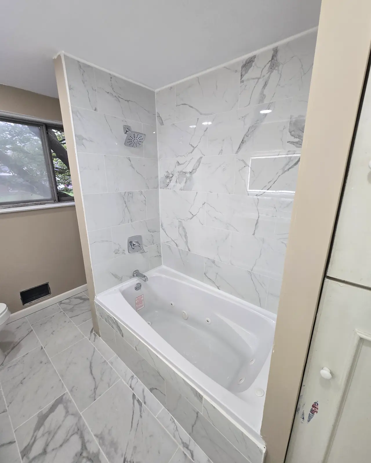 Tub with marble-look tile surround and a recessed niche