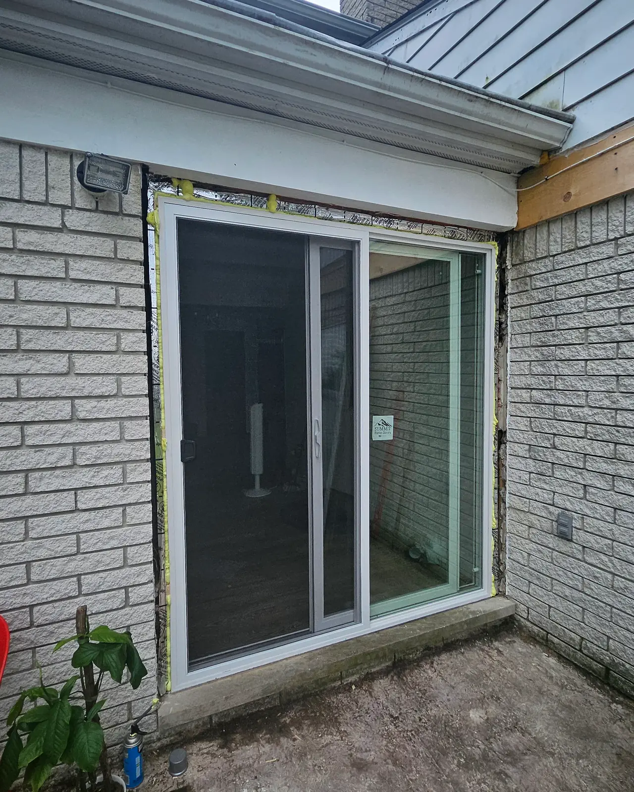 New white sliding patio door installed in the brick wall, after